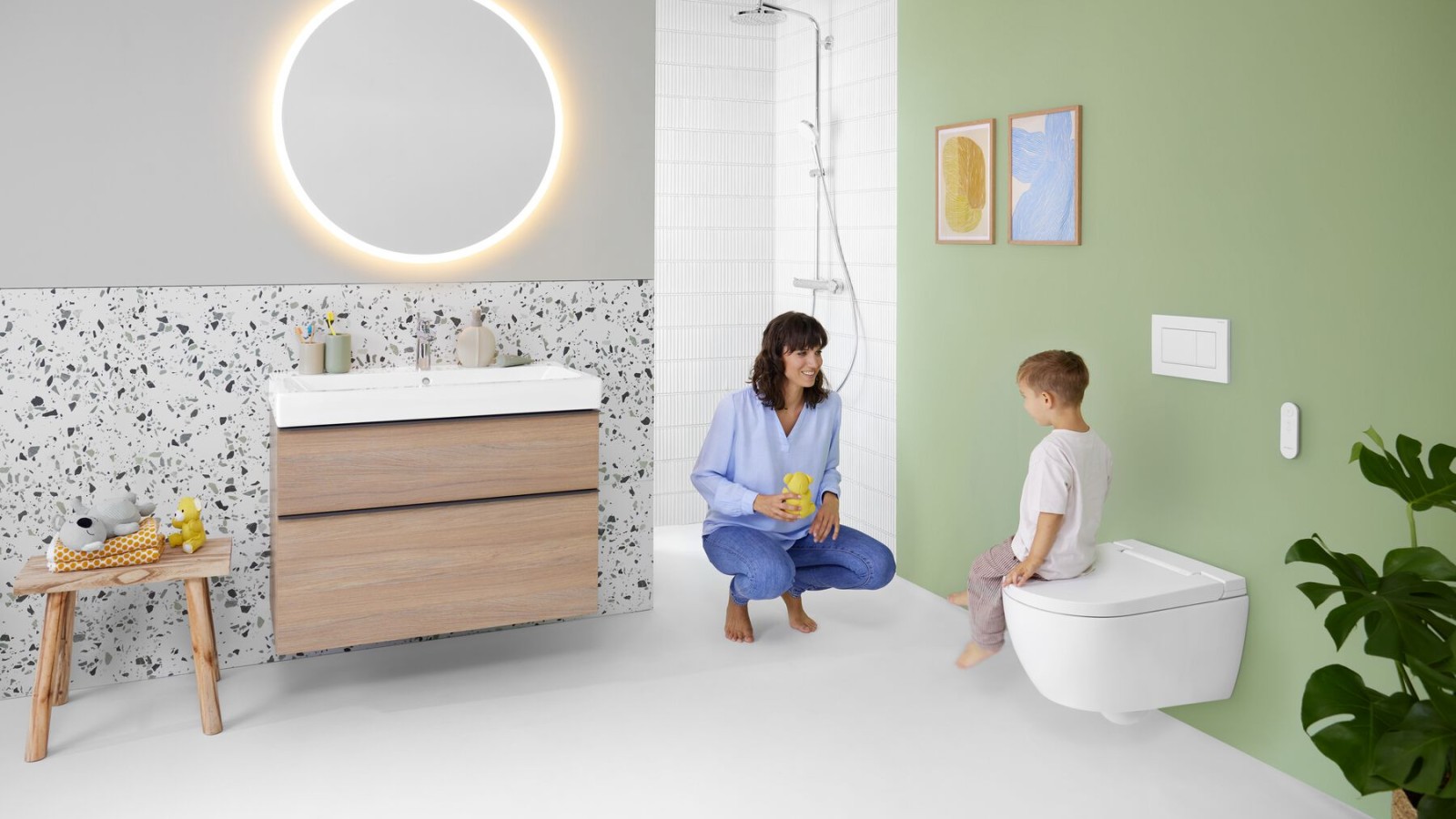 Naine ja laps värvilises vannitoas Geberit Optioni peegli ja Geberit AquaClean Albaga
